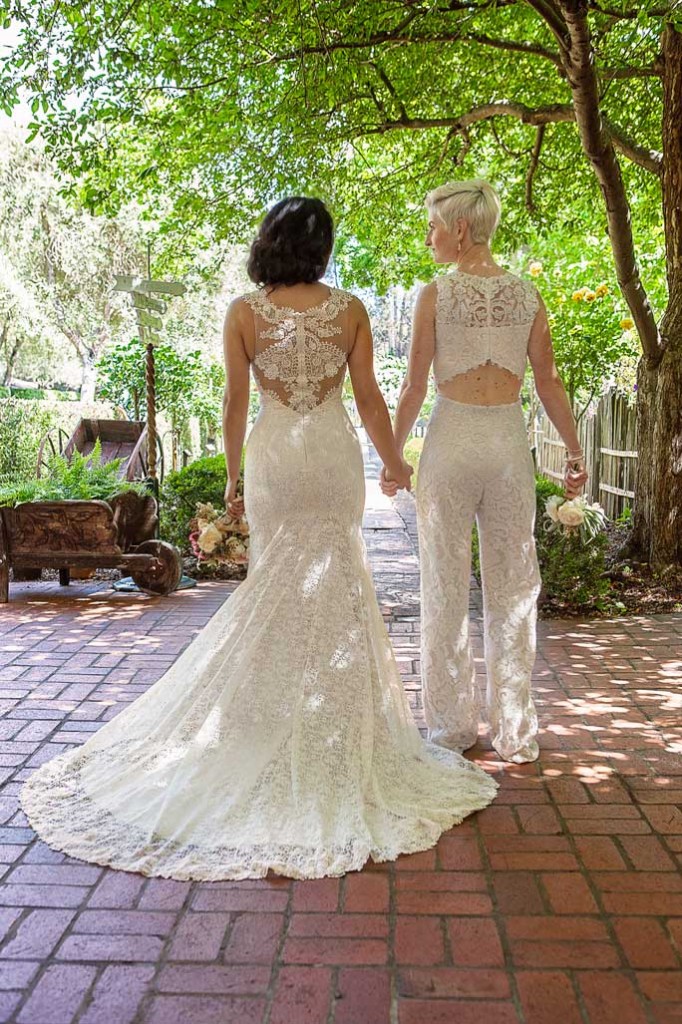 two lesbian brides at rustic Mexican wedding in a lace BHLDN wedding gown and lace jumpsuit with exposed back