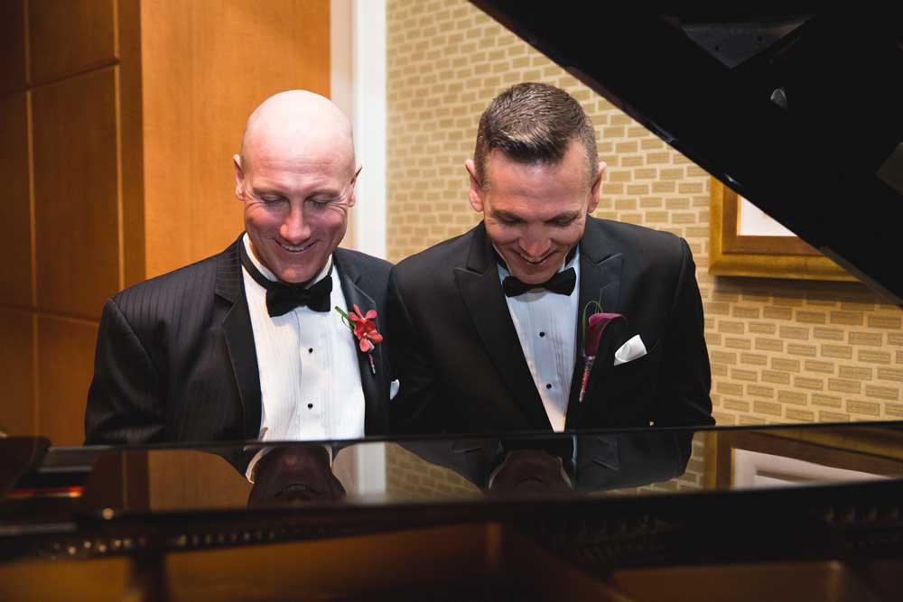 Gay couple on their wedding day playing piano together