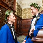 two grooms in blue suits smile at one another