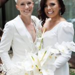 two brides post in white suits