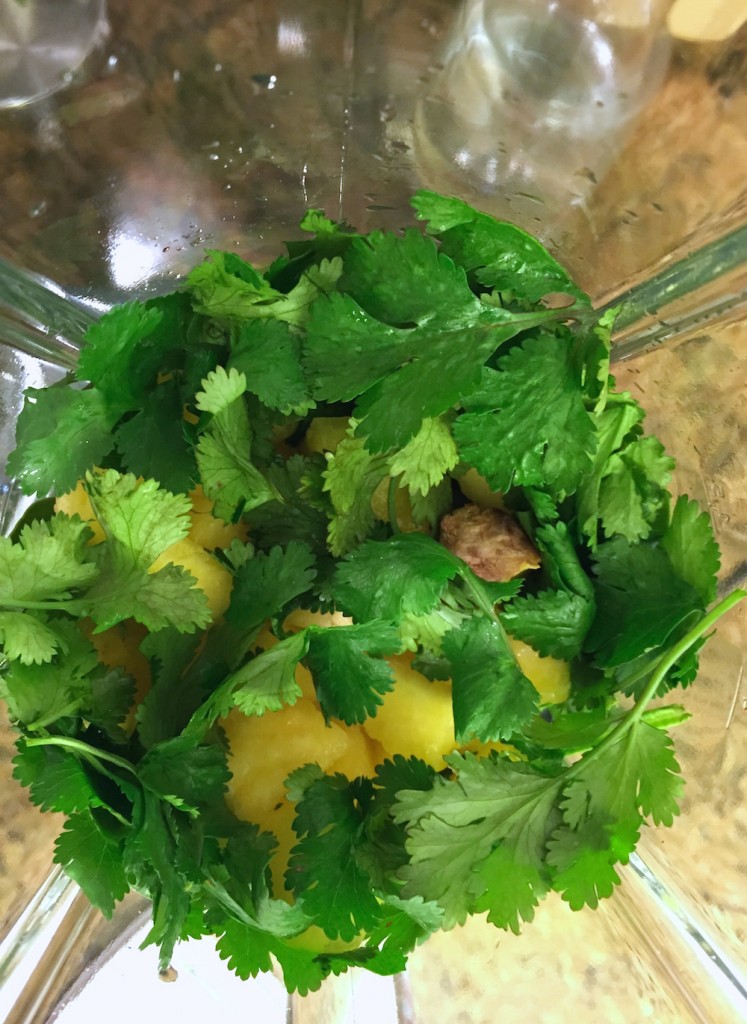 Top view of cilantro, ginger, lime juice, spinach, ice and pineapple.