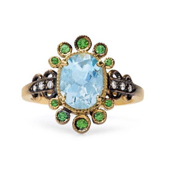 Raphaella is a vintage-inspired 18k yellow gold ring centering a stunning 1.72ct Oval Faceted aquamarine, casting a dreamy oceanic hue.