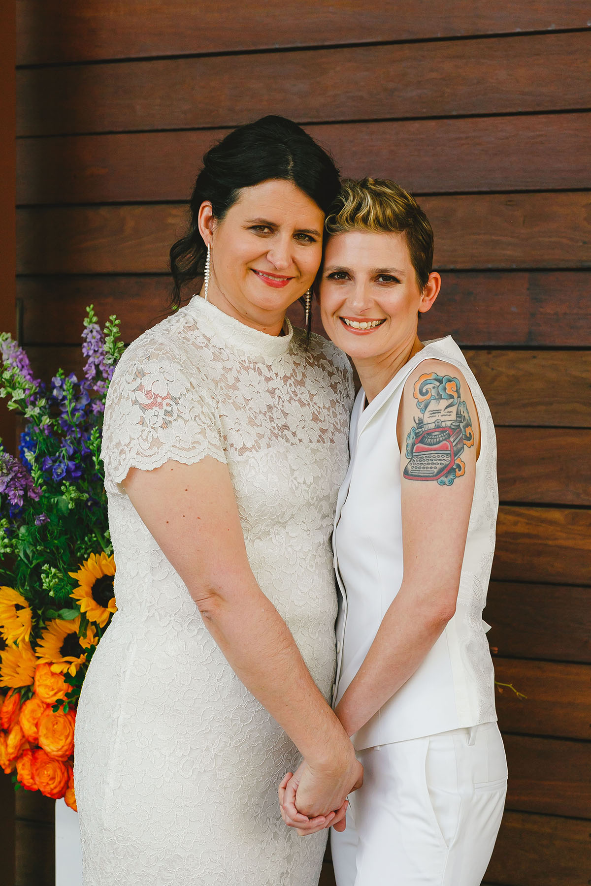 Colorful outdoor rooftop lesbian wedding in Austin, Texas holding hands