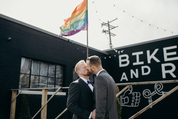 Fun, creative wedding in personal training studio rainbow flag kiss