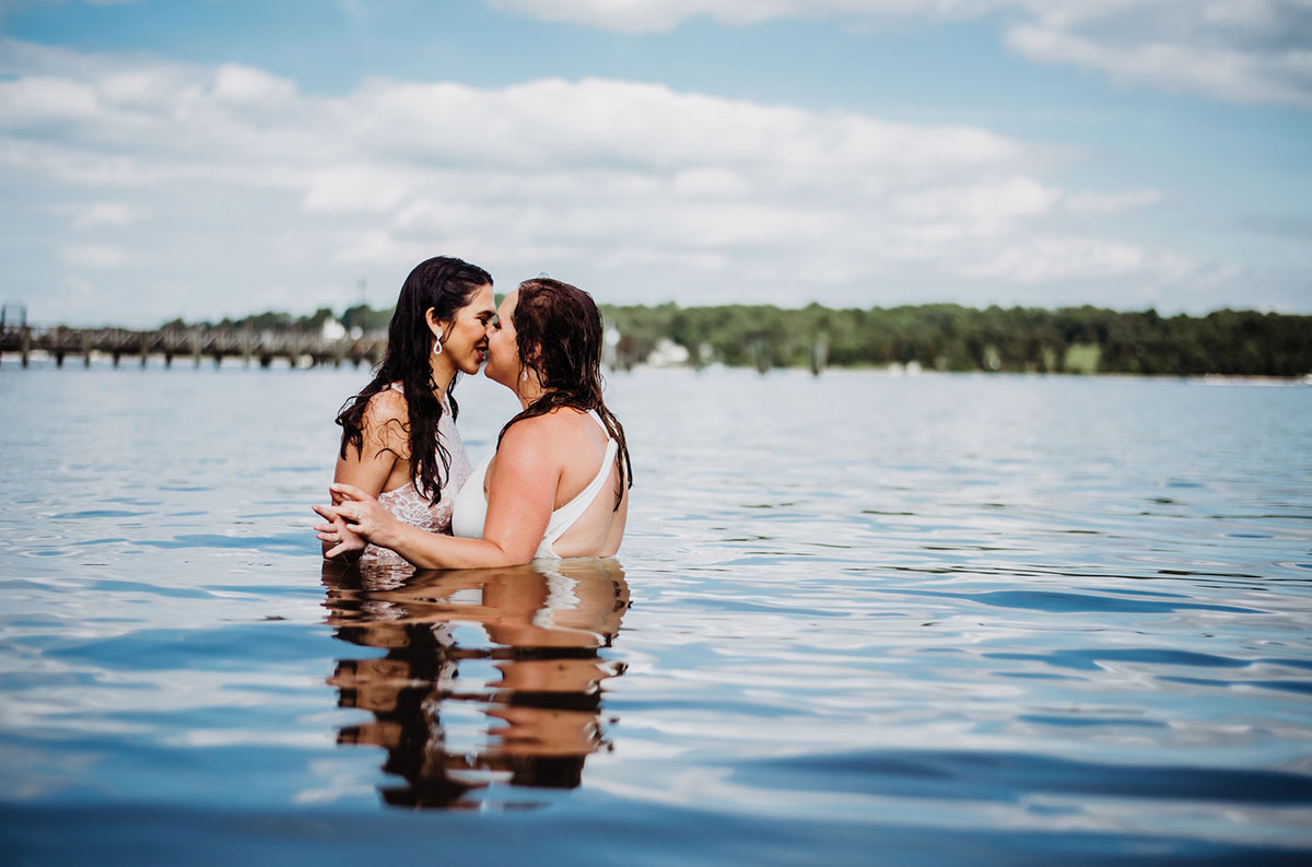Two brides trash their wedding dresses in a styled shoot water kiss