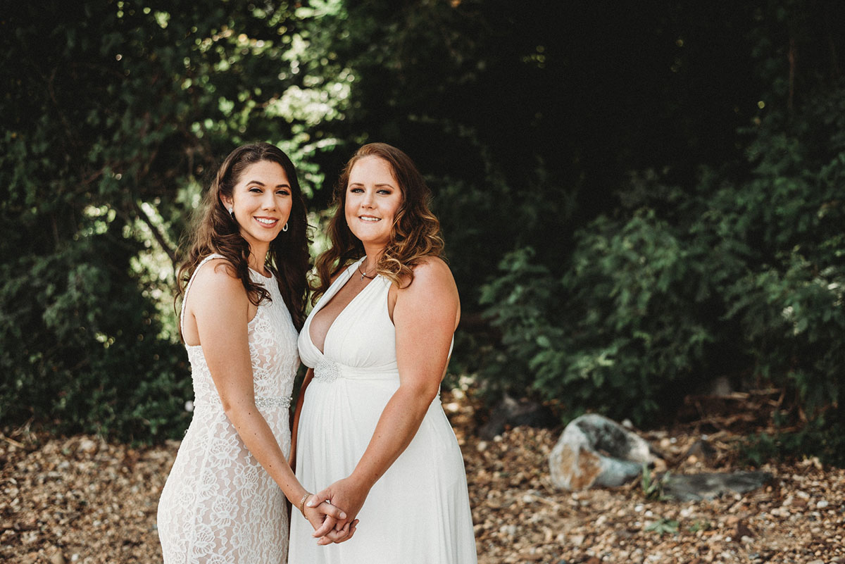 Two brides trash their wedding dresses in a styled shoot holding hands