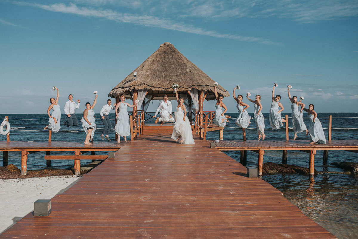 Cancun resort lesbian destination beach wedding Rachel Campbell Equally Wed brides jumping wedding party