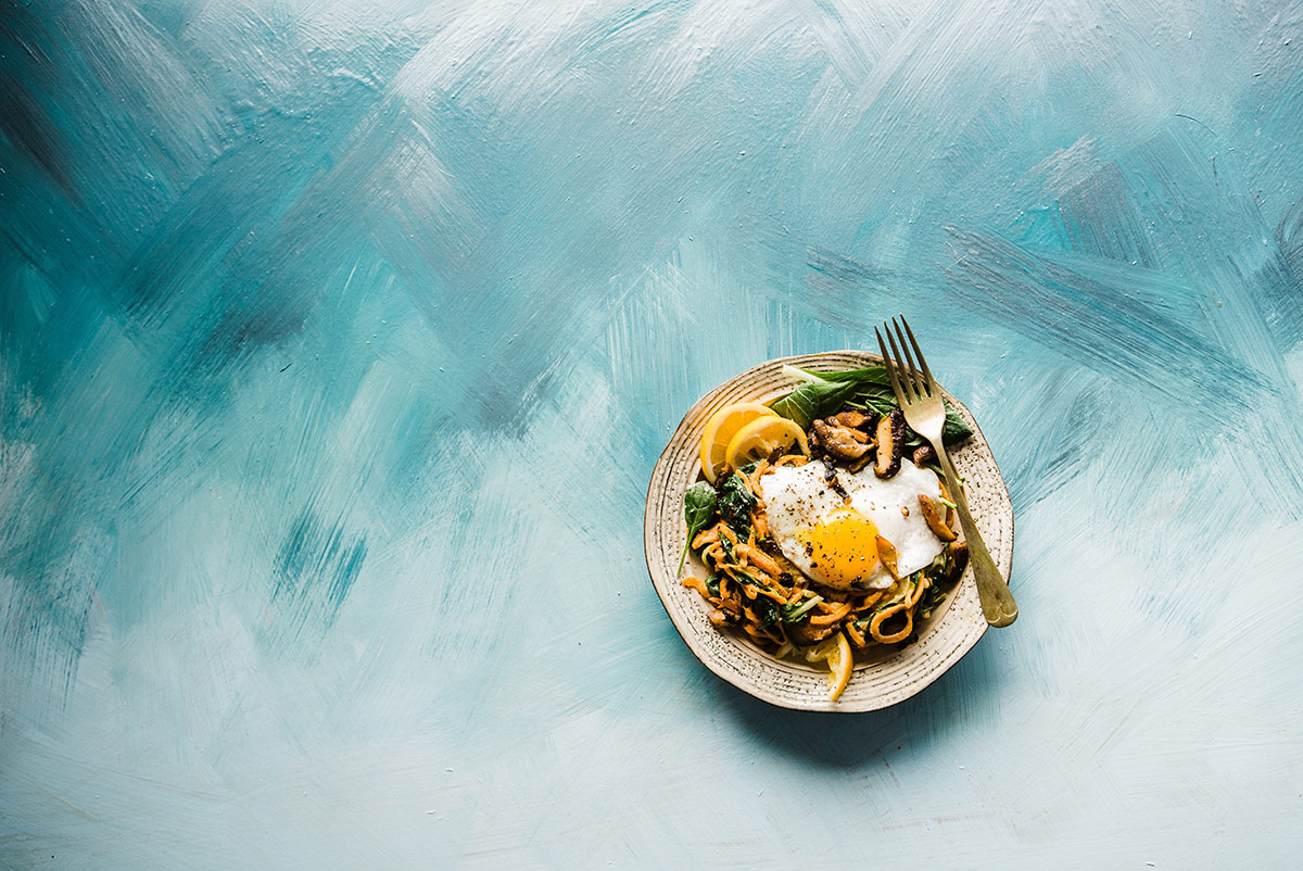 bowl of egg, lemon, greens, pasta against a blue watercolor print How to nourish your soul intentional mealtime mindful eating photo Brooke Lark Equally Wed