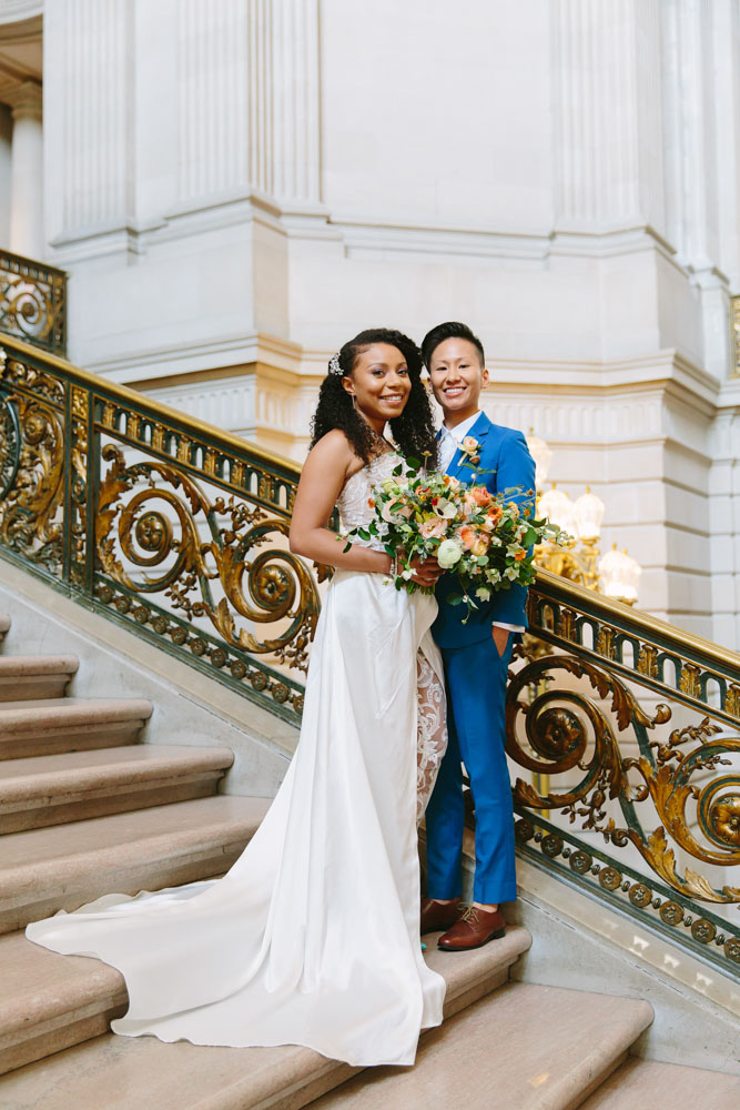 Actress Shalita Grant and commercial director Sabrina Skau married Aug. 8, 2018, in a San Francisco City Hall summer wedding. Shalita Grant wore a custom white gown with lace pants by Clara Diaz, and Sabrina Skau donned a custom blue suit from Bindle & Keep. Photography by Lilia Ahner. Featured on Equally Wed, a queer-owned LGBTQ+ wedding magazine.