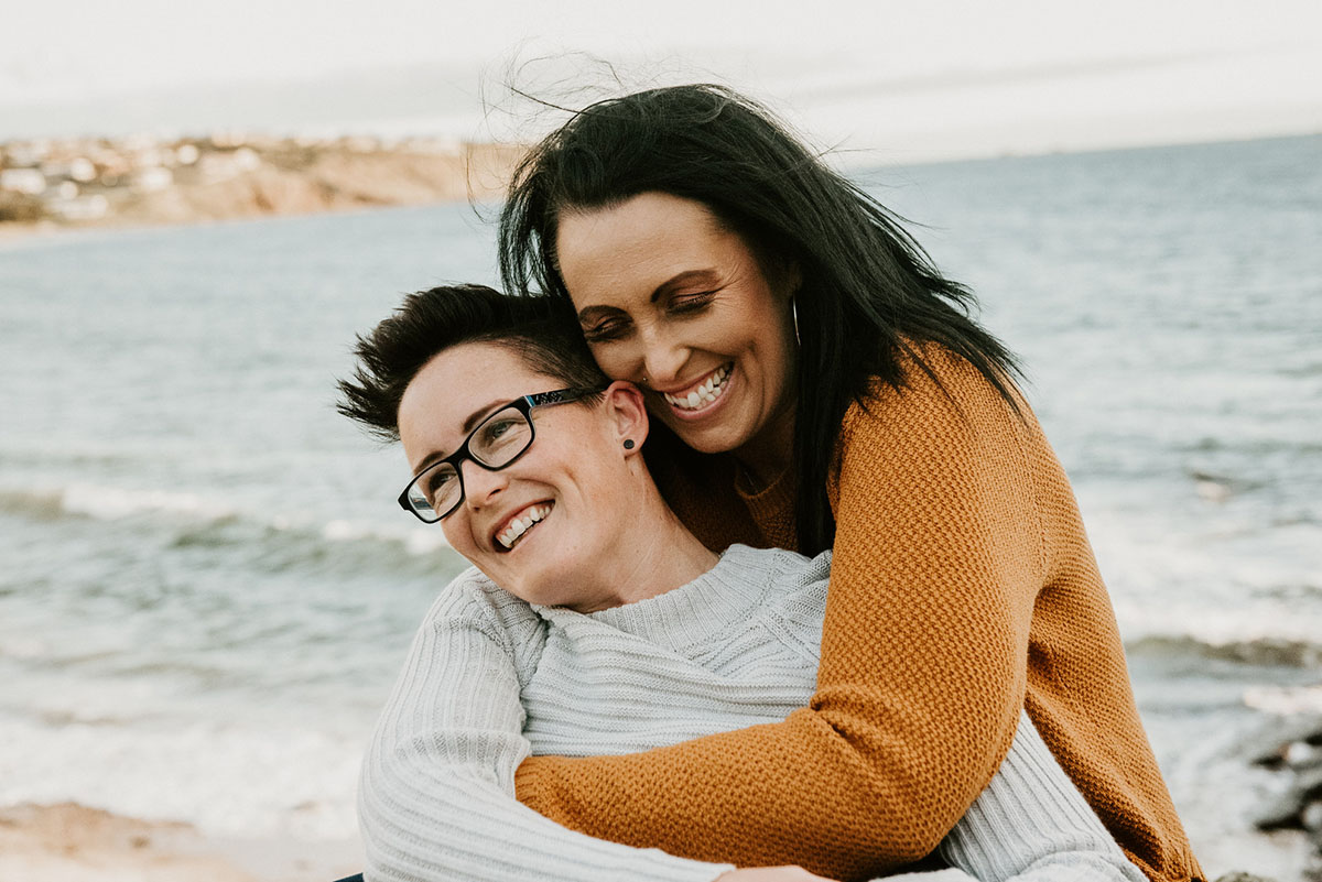 Same-sex engagement photography session on the coast of South Australia hugs beach