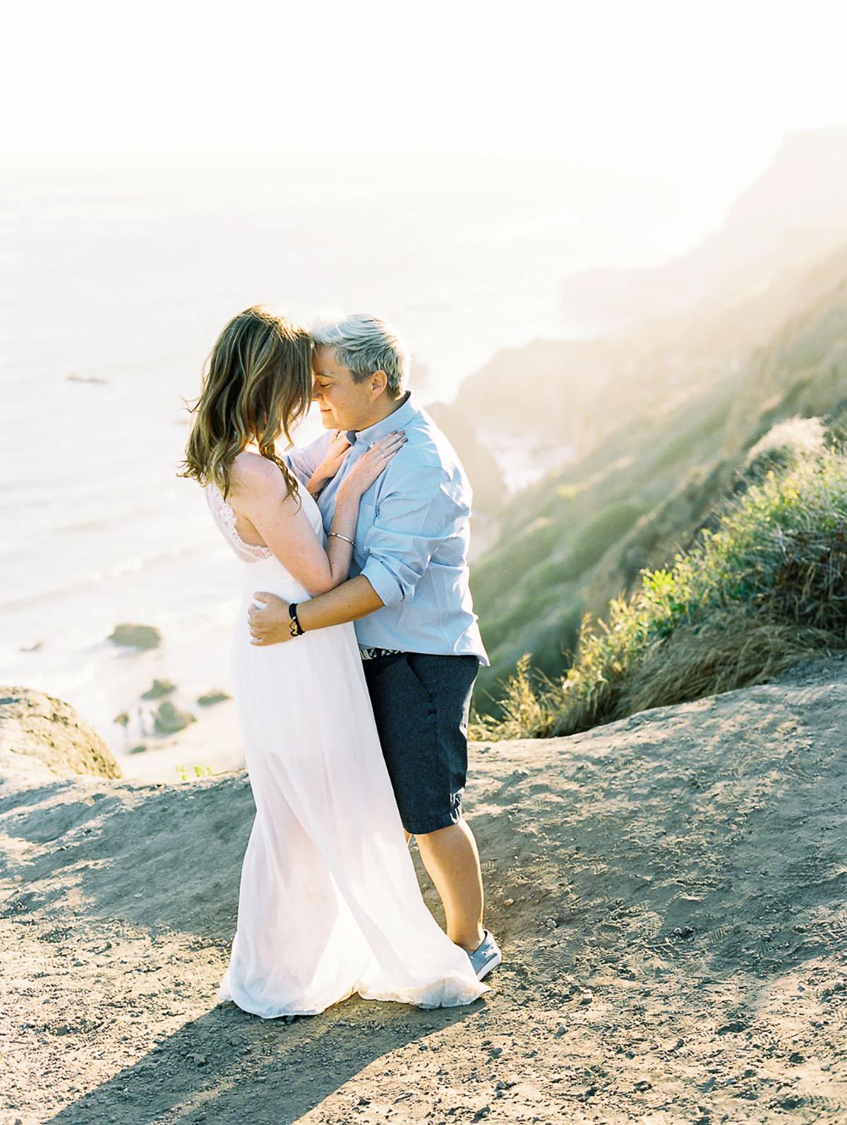 Beach engagement at El Matador State Beach in Malibu, California embrace two brides