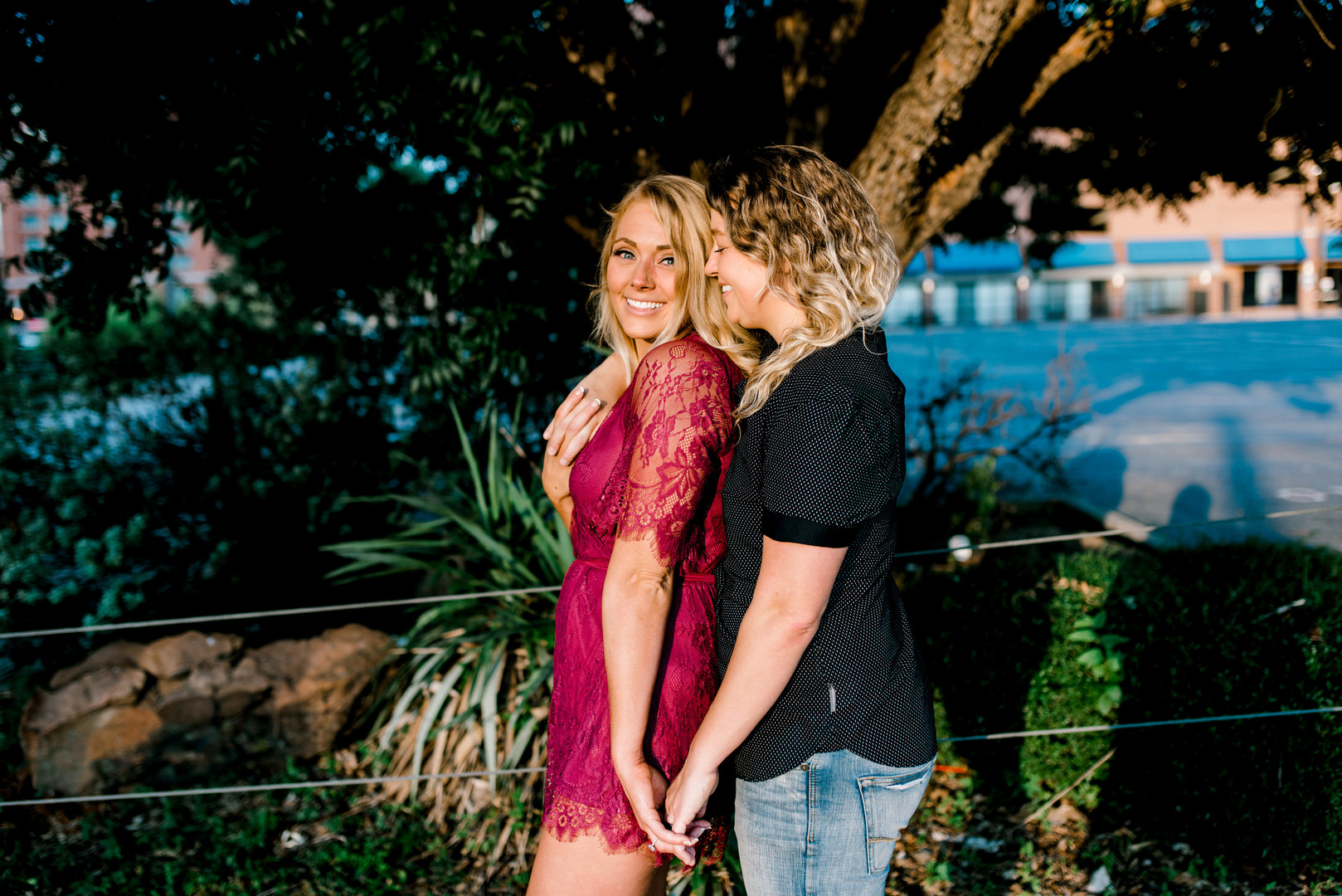 Bright, floral engagement session in downtown Dallas, Texas two blonde brides ring casual sunrise jeans red lace dress heels boots early morning