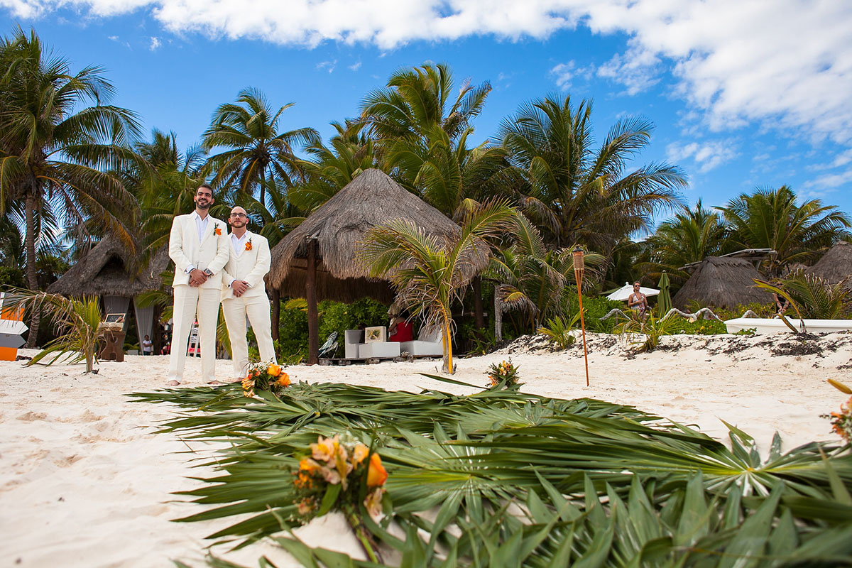 Destination Mexican beach wedding at Akiin Tulum two grooms white suits tuxedos hut palm trees
