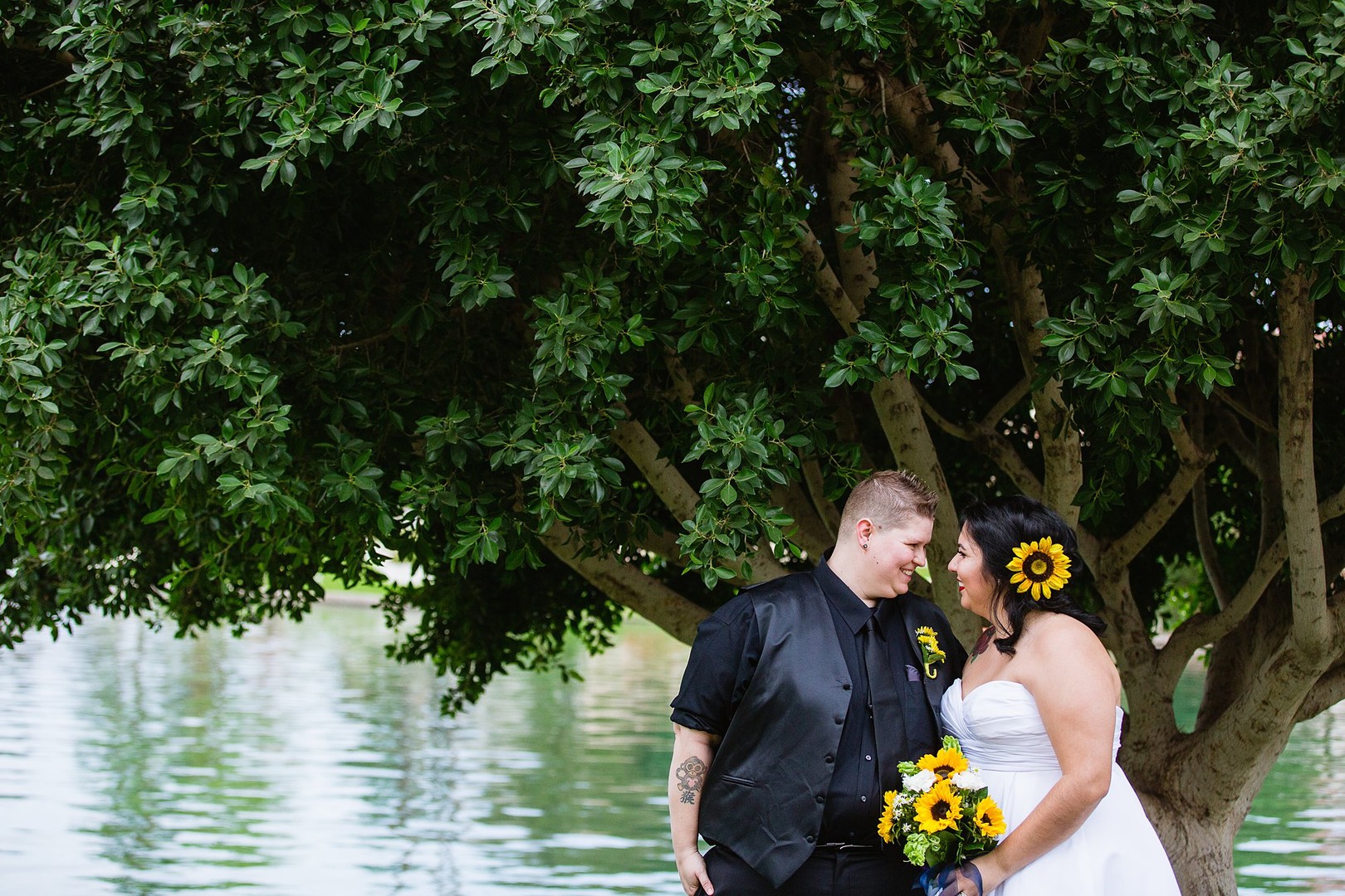 Fun and romantic Arizona backyard wedding lesbian two brides sunflowers bouquet tuxedo white dress lake