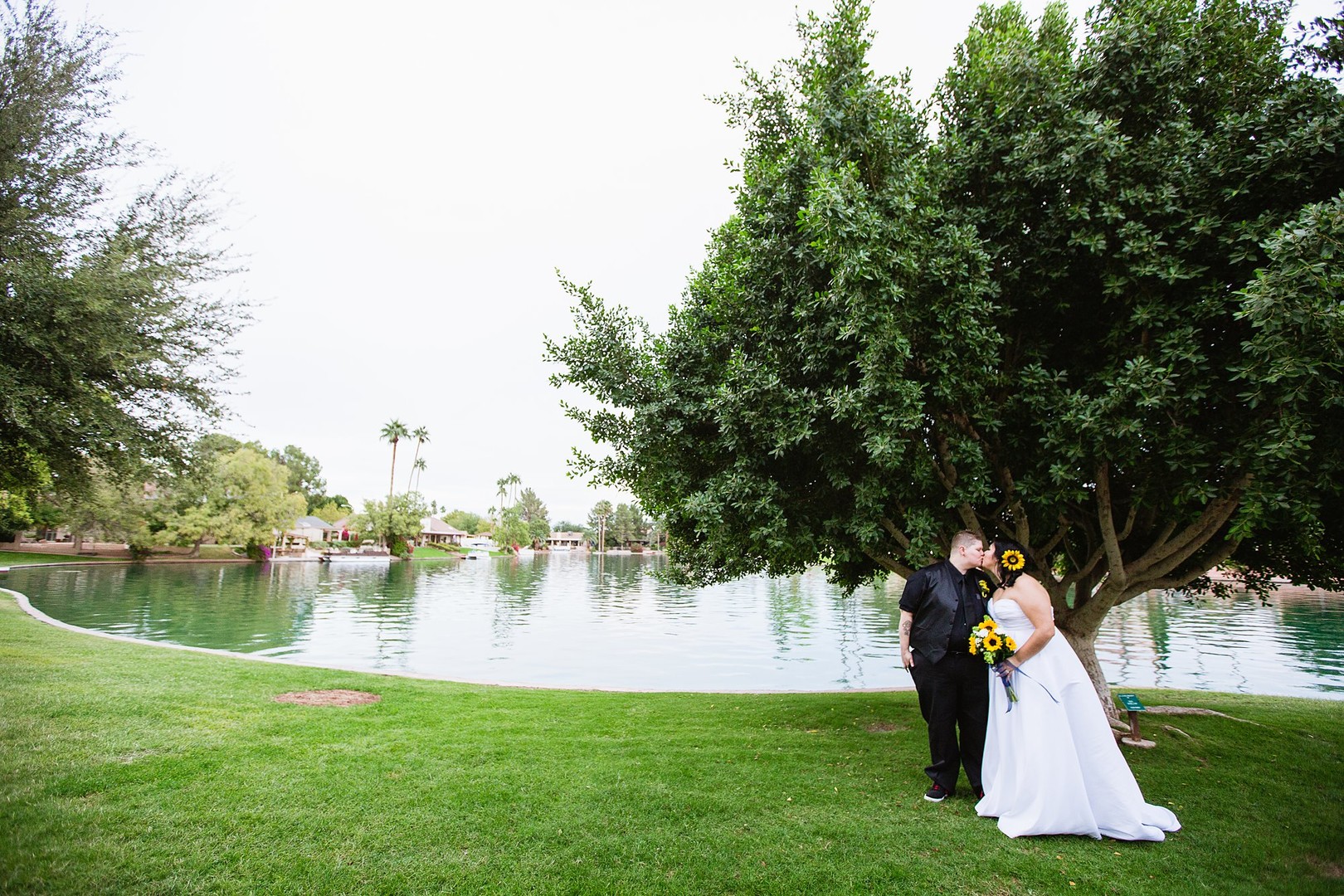 Fun and romantic Arizona backyard wedding lesbian two brides sunflowers bouquet tuxedo white dress lake