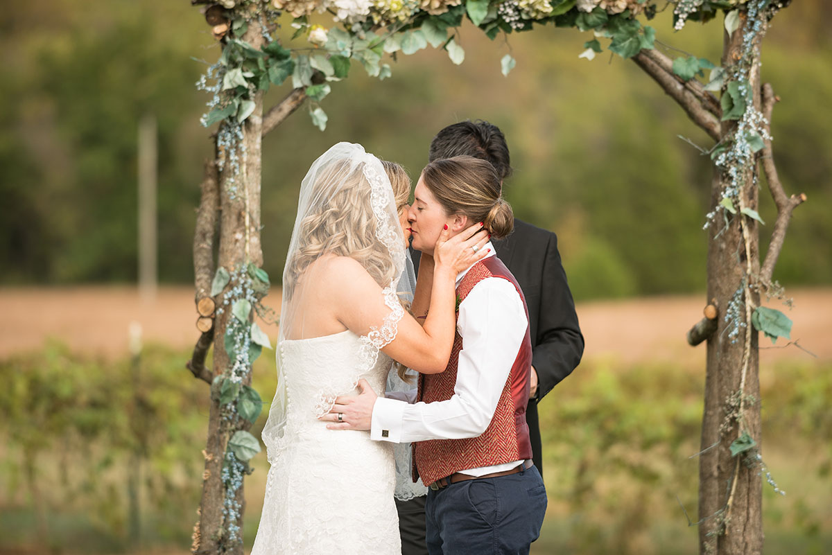 Rustic traditional Southern fall wedding in a barn veil white dress cowboy boots vest Saint Louis two brides kiss just married