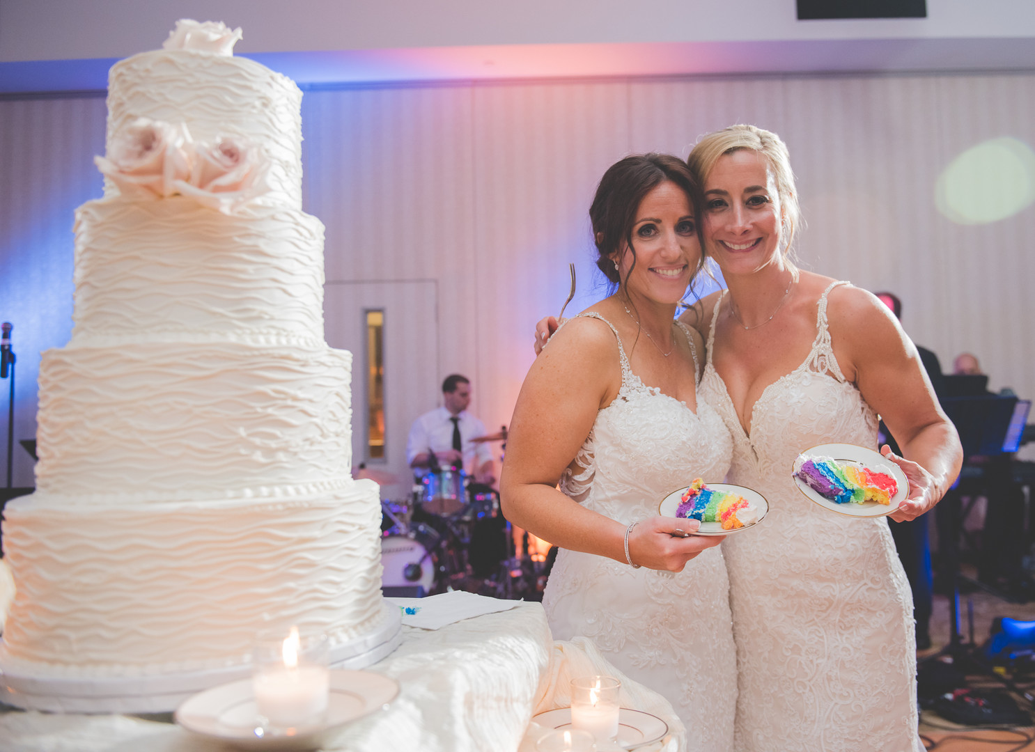 Traditional Jewish wedding during Pride Month two brides up-do long white lace dresses wedding cake rainbow