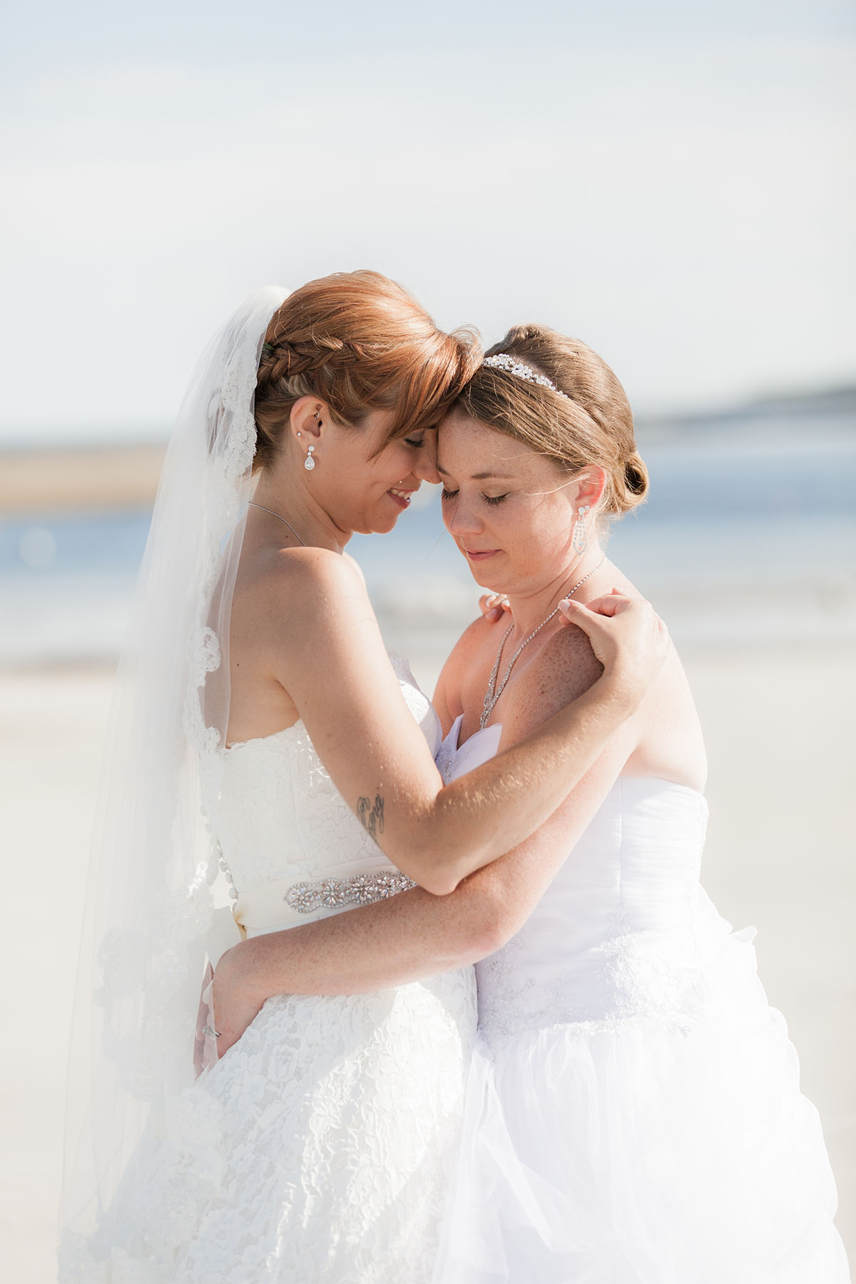 Beach wedding in Kennebunkport, Maine two brides long white dresses summer bouquets cuddling intimate