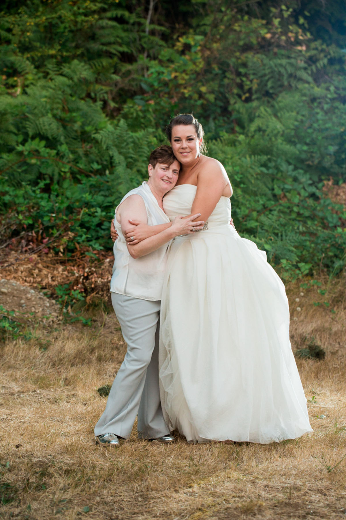 Purple Northwest backyard wedding two brides white dress white tuxedo cuddling woods
