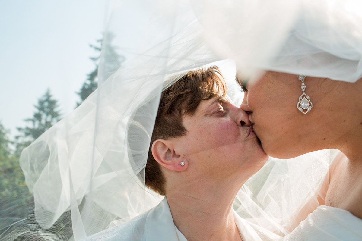 Purple Northwest backyard wedding two brides white dress white tuxedo veil kiss