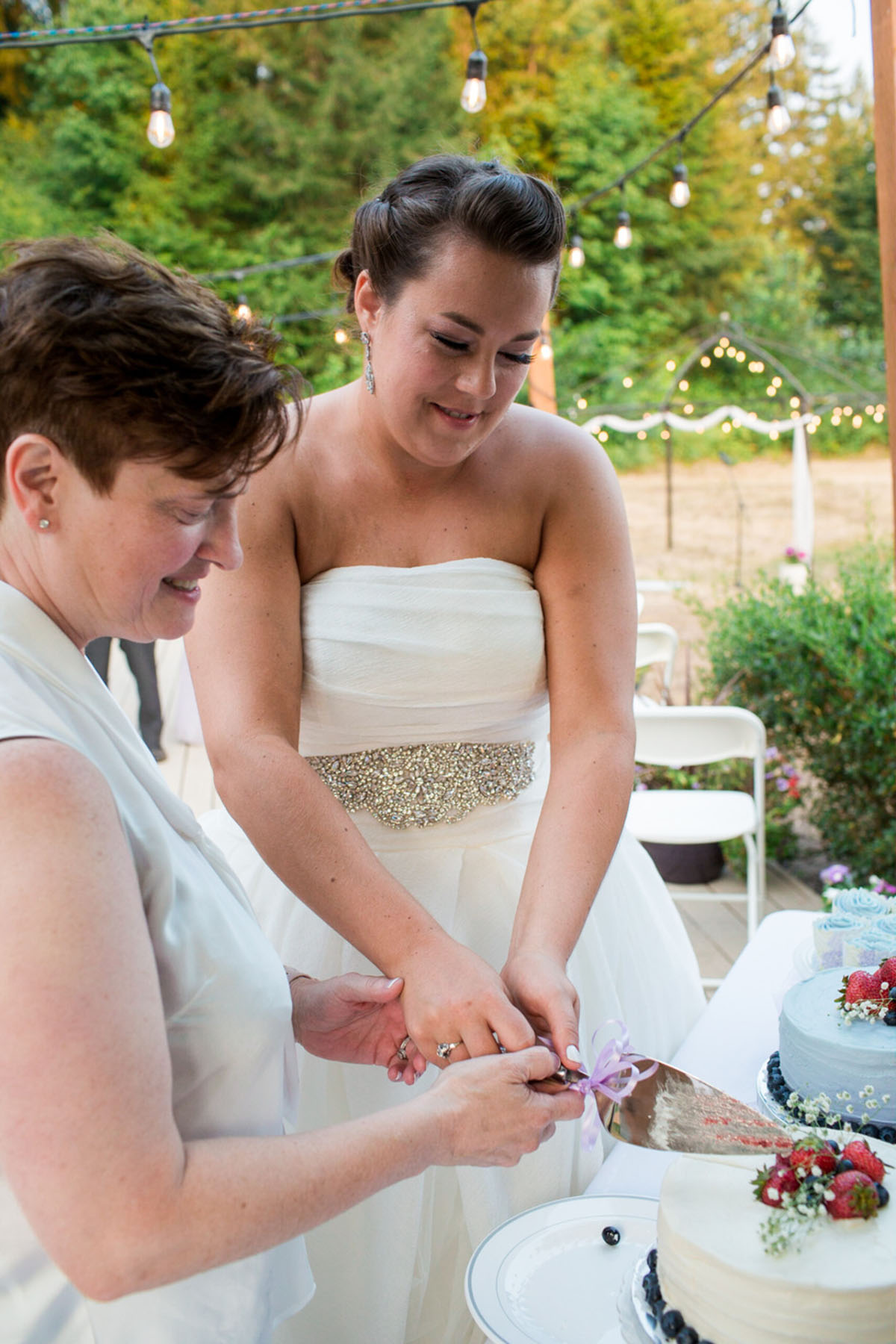 Purple Northwest backyard wedding two brides white dress white tuxedo cake cutting