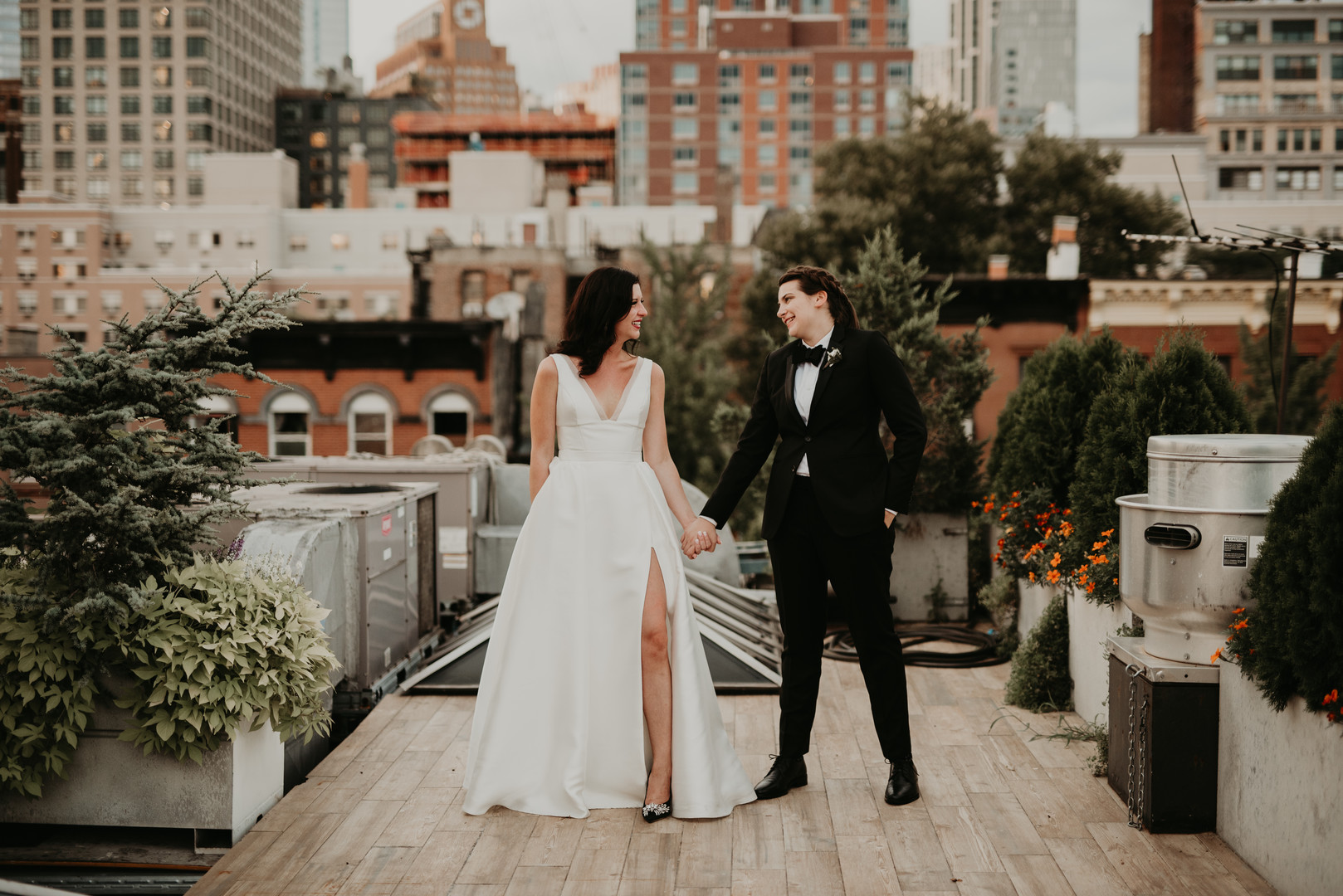 Purple and black rooftop wedding in Brooklyn, New York two brides black tuxedo V-neck white dress sunset skyline