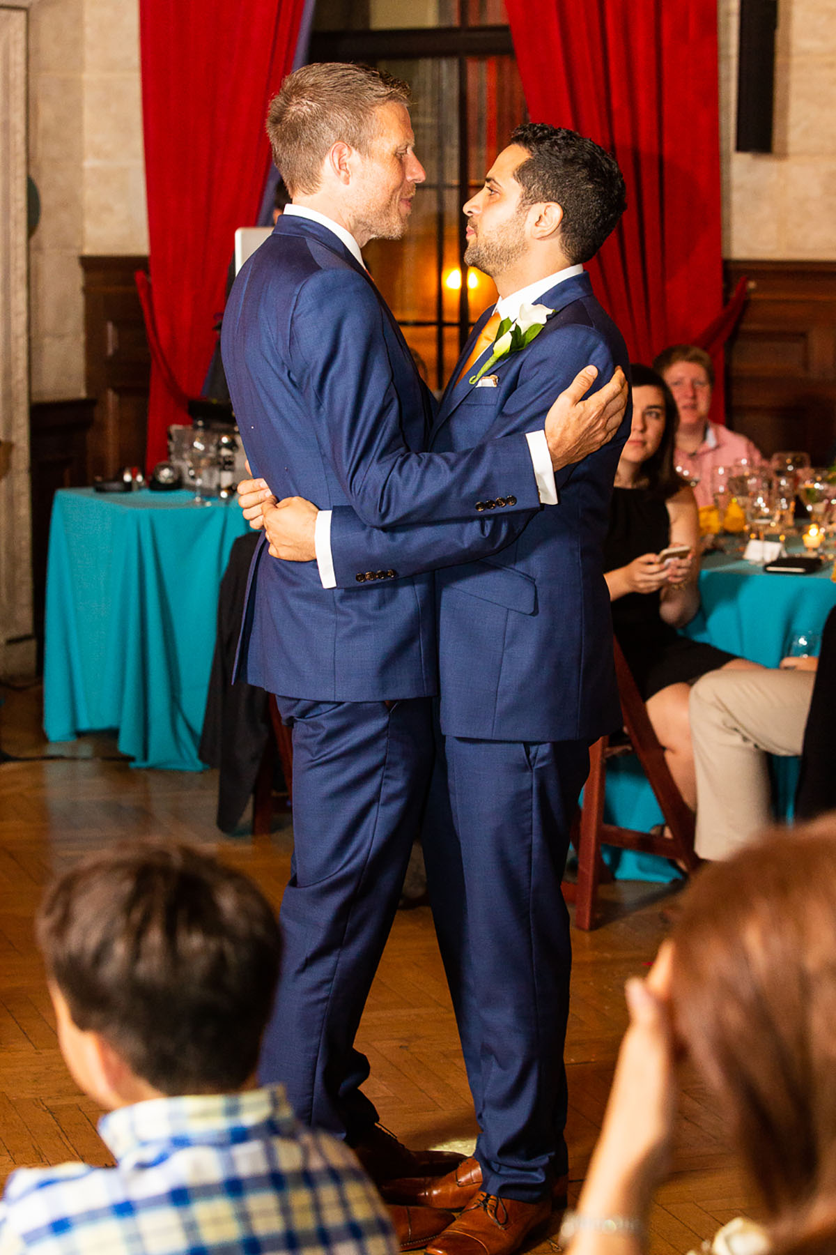 Romantic, artsy New York City wedding red backdrop blue tuxedos pink gold ties two grooms