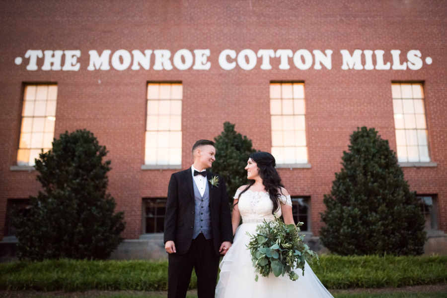 Vintage travel inspired wedding in Monroe, Georgia exposed brick industrial building two brides long white dress veil black tuxedo cotton mill