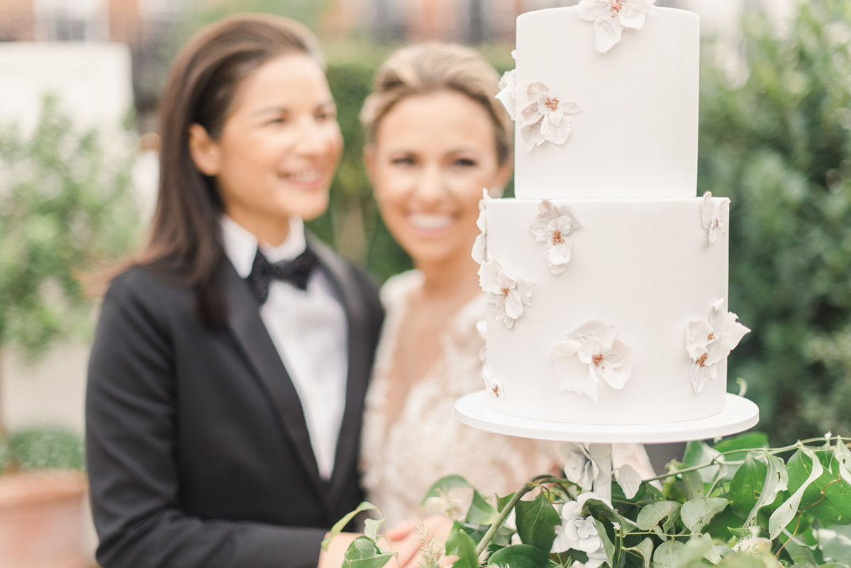 Floral wedding inspiration in New Orleans, Louisiana two brides black tuxedo bow tie long sleeve lace white dress cake