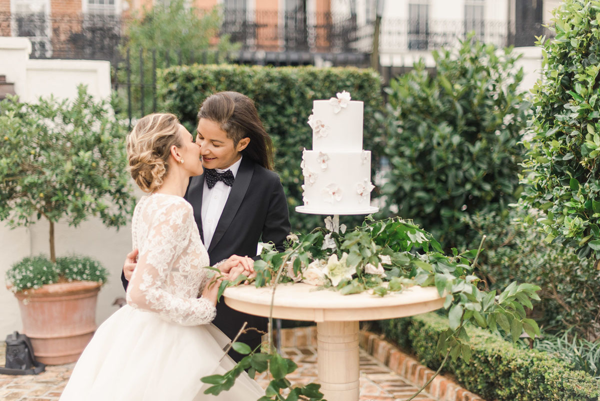 Floral wedding inspiration in New Orleans, Louisiana two brides black tuxedo bow tie long sleeve lace white dress cake greenery