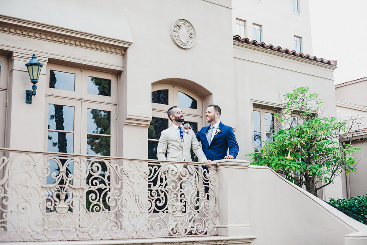 Historic hometown wedding in Pasadena, California two grooms blue tux gray tux boutonnieres outside porch