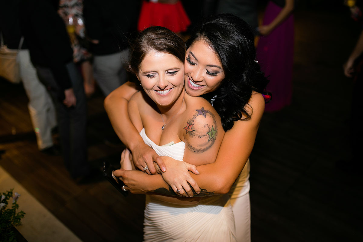 Modern rooftop wedding in Kansas City, Kansas Asian-American lesbian wedding long white dresses hug from behind