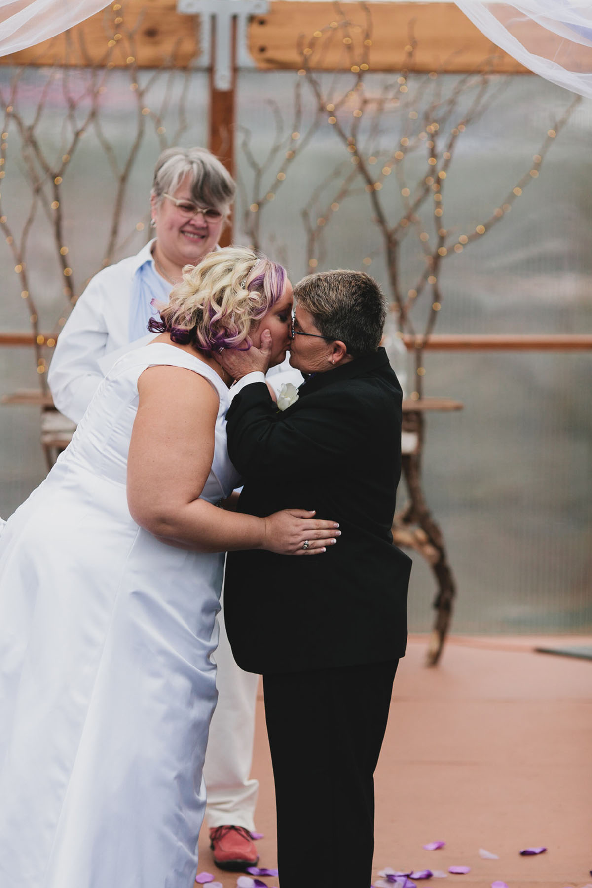 Purple greenhouse wedding with goats two brides lesbian wedding black tuxedo white dress kiss
