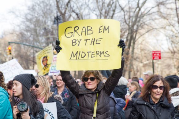 All the LGBTQ+ news from the 2018 midterm elections sign that says Grab em by the midterms peaceful protest march gathering activism