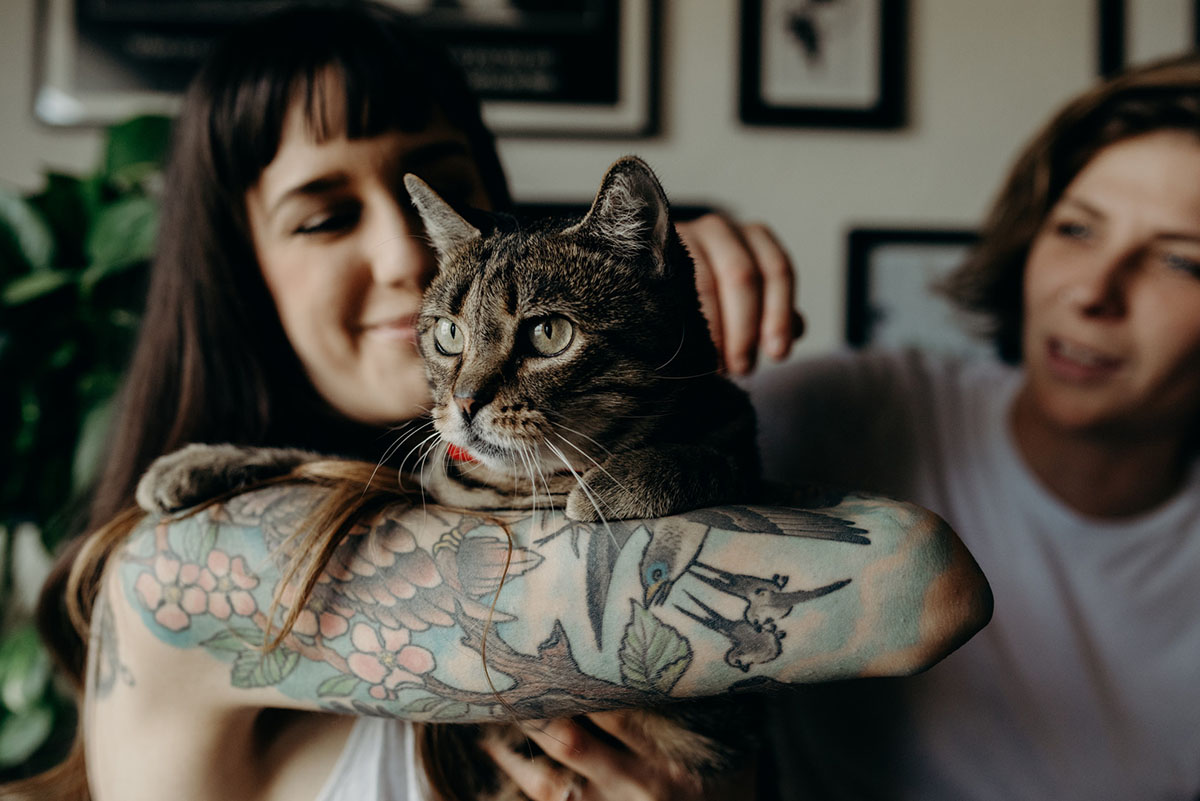 Home engagement photos with cats in San Diego, California two brides lesbian couple overalls plants rooftop garden tabby tuxedo cat tattoos intimate casual