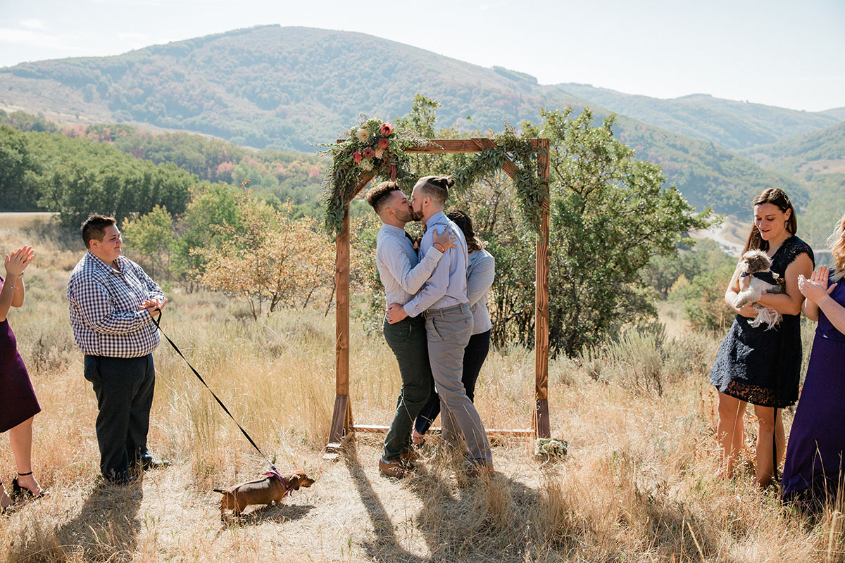 Rustic mountain wedding at the Art Nord Trailhead two grooms suspenders bow tie Syracuse, Utah short ponytail kiss