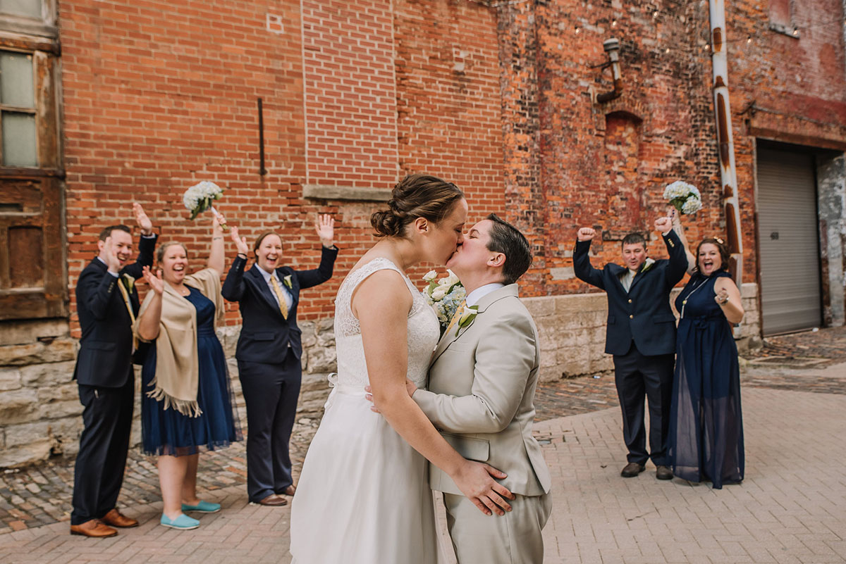 Rustic winery wedding in Columbus, Ohio exposed brick grey tuxedo long white tulle dress two brides kiss