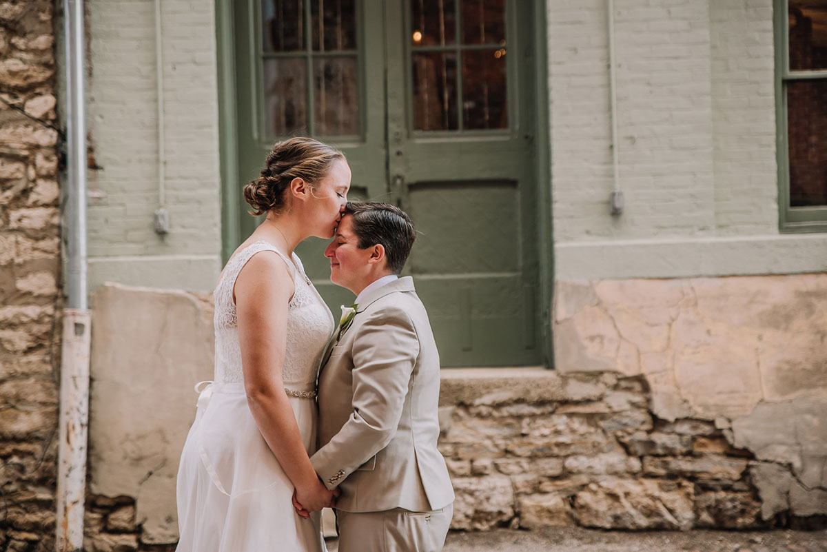 Rustic winery wedding in Columbus, Ohio exposed brick grey tuxedo long white tulle dress two brides forehead kiss
