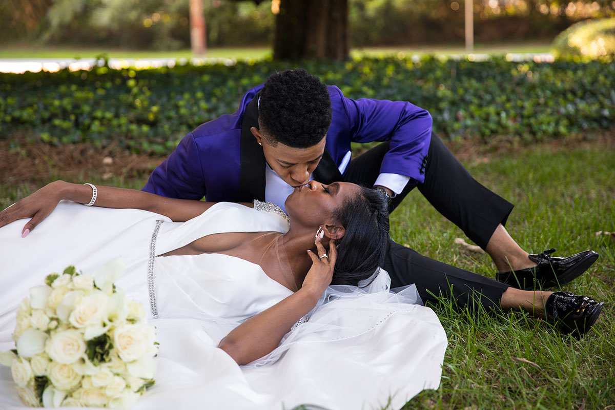 Southern traditional chapel wedding two brides purple tuxedo long white dress church God religious cultural traditions laying down grass