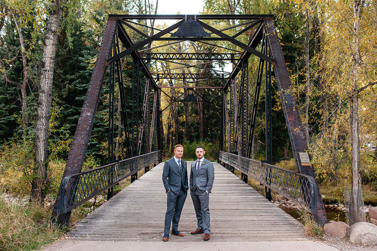 Fall mountain wedding in Aspen, Colorado two grooms steel grey tuxedos patterned ties bridge