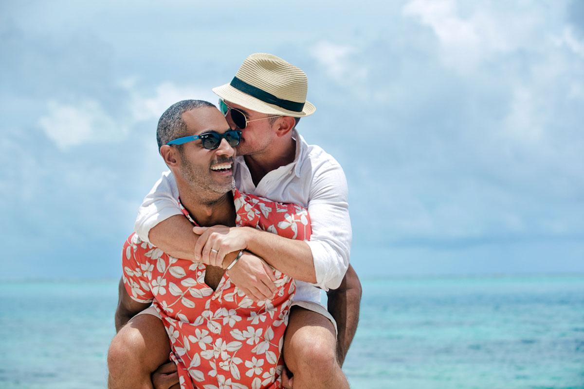 Tropical honeymoon photos on Mo'orea Island two grooms shorts floral pink shirt button down piggyback beach