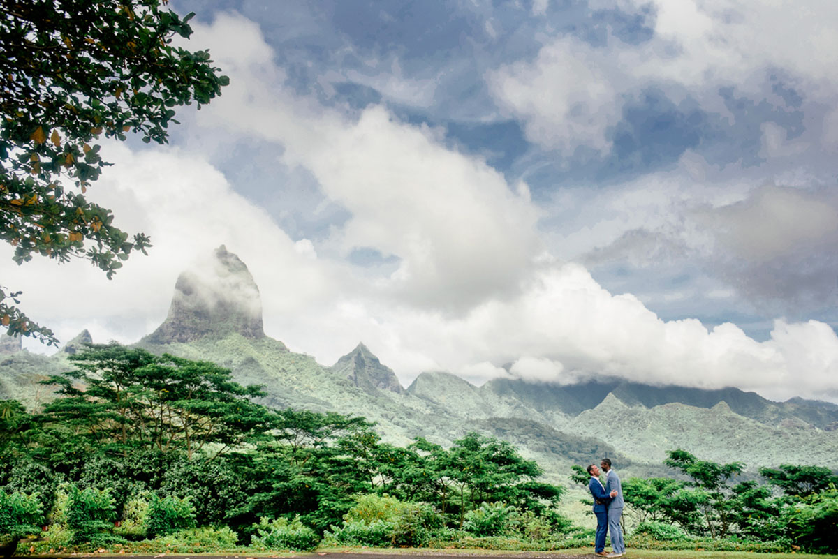 Tropical honeymoon photos on Mo'orea Island two grooms grey suit blue suit mountains outside