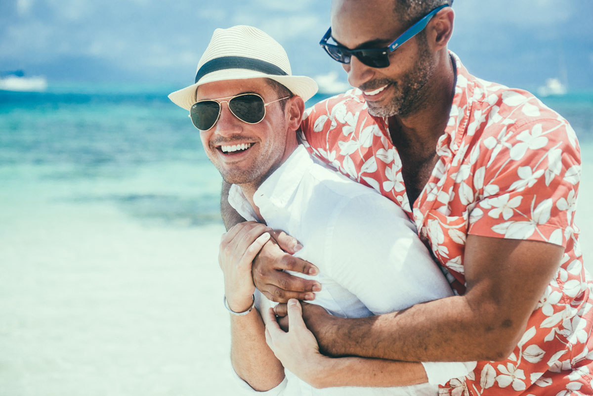 Tropical honeymoon photos on Mo'orea Island two grooms shorts floral pink shirt button down cuddling beach