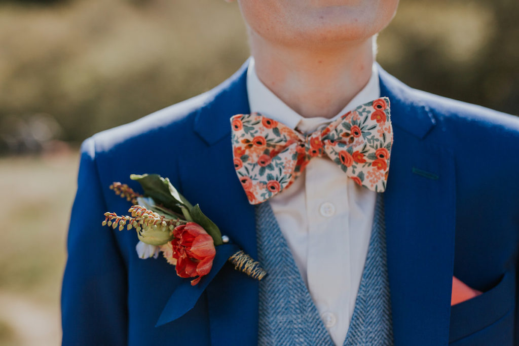 10 LGBTQ+ wedding details colorful attire blue suit with light blue vest and oversized floral bow tie Equally Wed