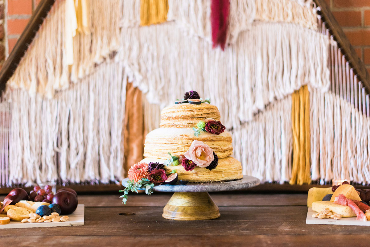 Bright bohemian wedding inspiration two brides burgundy red tux white dress colorful flowers long veil tiered cake