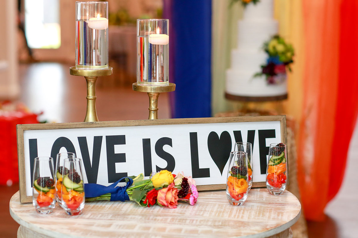 Fun rainbow wedding inspiration for people who want to elope love is love sign vivid bright flowers cocktails