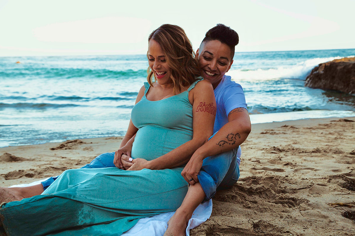 Stunning waterfront photos to celebrate IVF and starting a family two moms pregnancy lgbt family long teal dress maternity