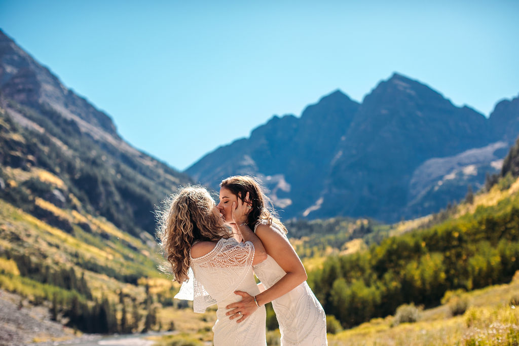 Intimate Elk Mountains wedding in Aspen, Colorado two brides bohemian mountain elopement white dresses kiss