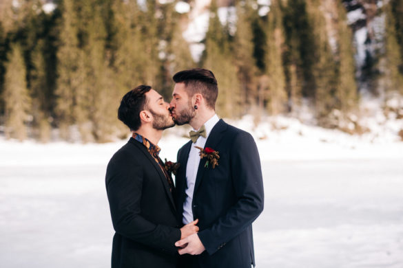 This winter mountain elopement on the Dolomites in Italy is seriously cozy two grooms black tuxedos tux snowy March mountains Lake Braies kiss