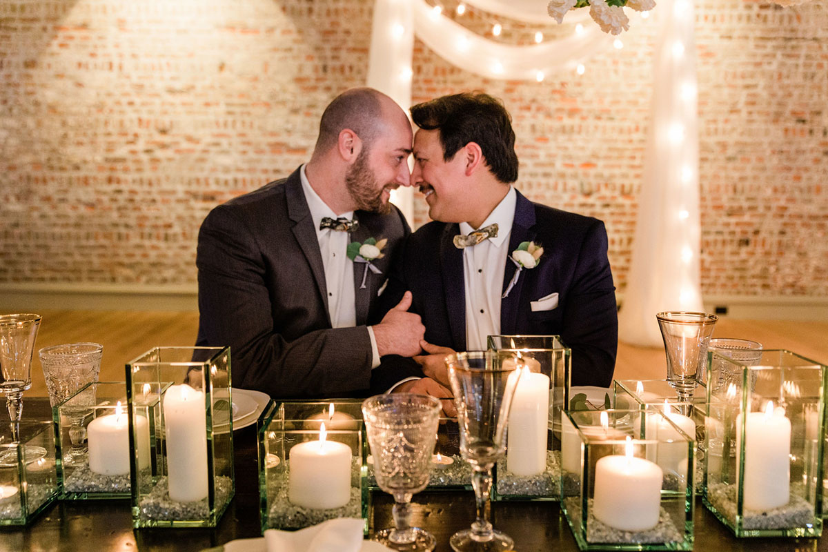 Rustic and romantic wedding inspiration in Charleston, South Carolina two grooms blue tux gray tux oyster shell bow ties fairy lights brick wall